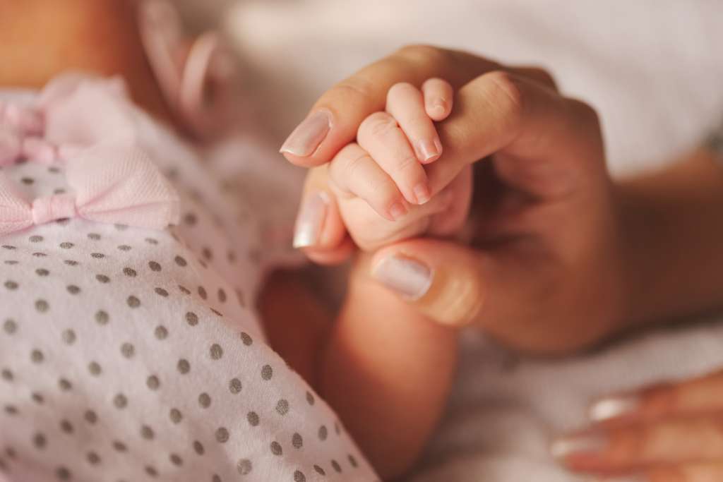 Mother holding new born hand