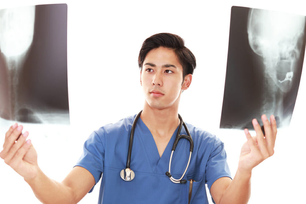 A photograph of a young doctor holding radiographs. This is the type of dcotr who might be involved in the doctors' strikes