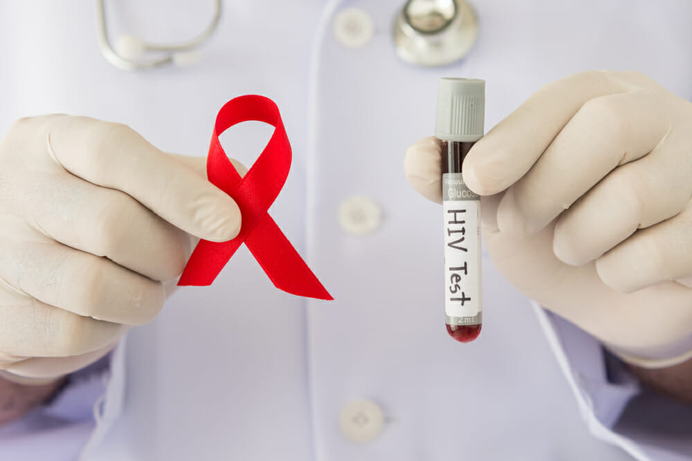 A person holding the red ribbon HIV and AIDS and a blood sample.