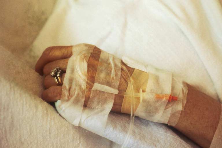 A close up photograph of hand receiving IV chemotherapy in an article about Waiting times for cancer treatments increasing.