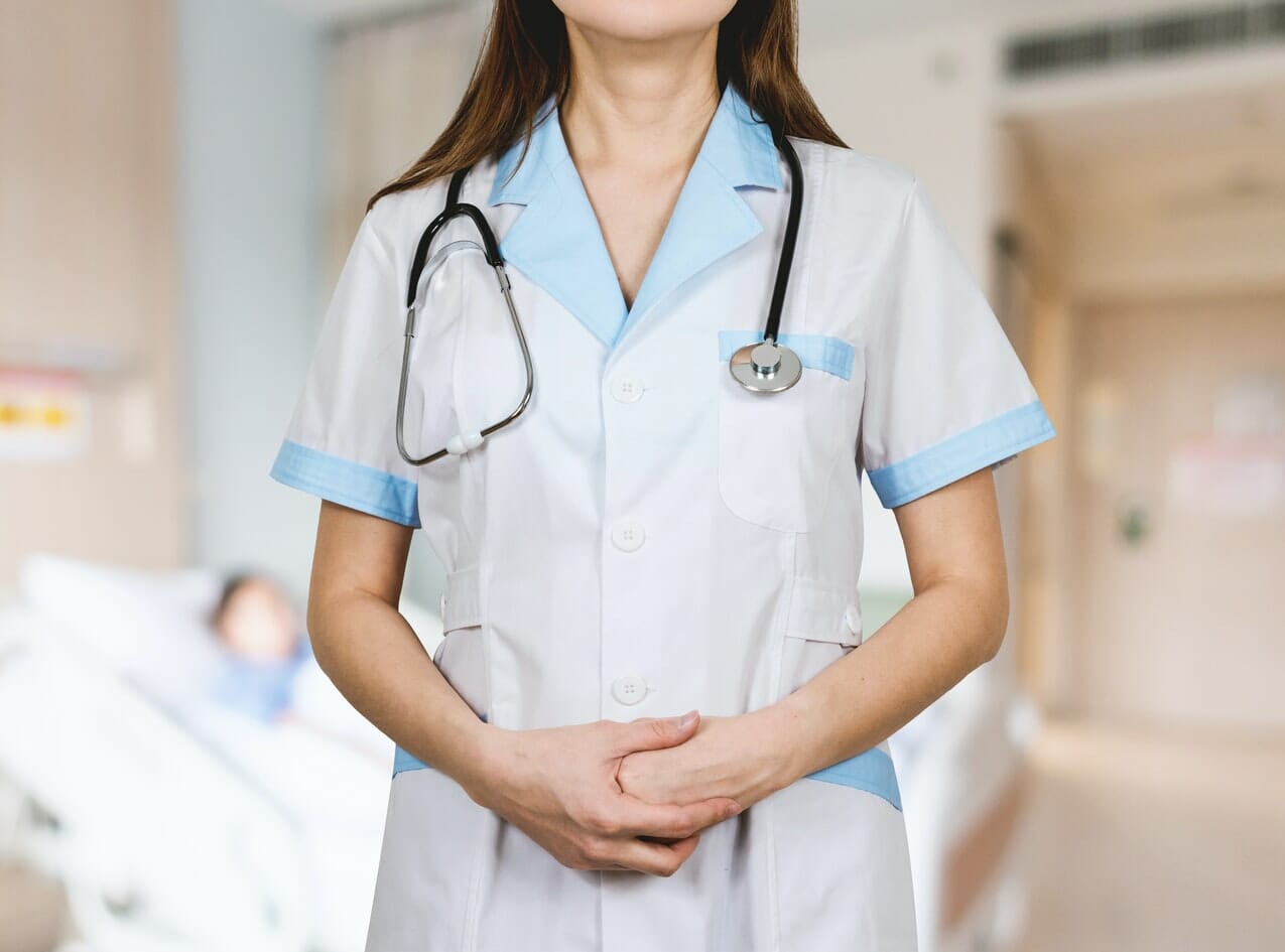 A photograph of a nurse. The image shows her looking towards the camera, but only shows her torso. This is the type of recruit NHS apprenticeships would be looking to train up.