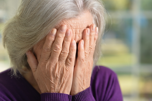 sad elderly woman with her face in her hands