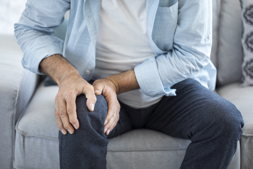 man with knee pain holding his knee