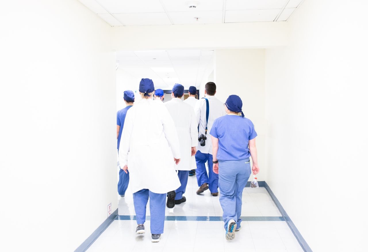 A photograph of medical professionals walking away, as Brexit, stress and pressure is blamed on the nurse shortage in the UK