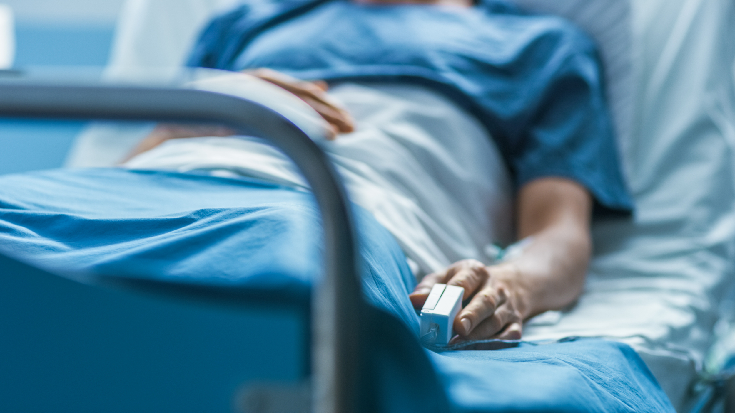 A photograph of a man lying in a hospital bed