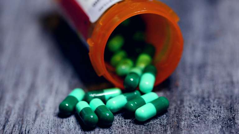 A photograph of green capsule medication from a prescription bottle, to depict the risk of opioid addiction patients are being subjected to.