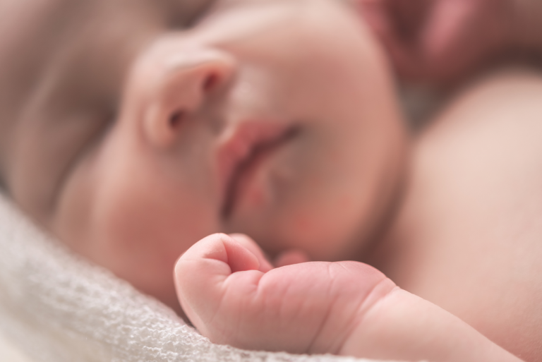 A photograph of baby's hand in front of it's face, in soft focus. Potter's syndrome can lead to underdeveloped lungs and kidney abnormalities in babies, but it is often detected during pregnancy.