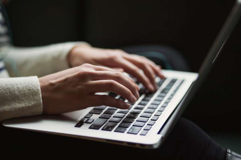 A person typing on a laptop keyboard - NHS Complaints