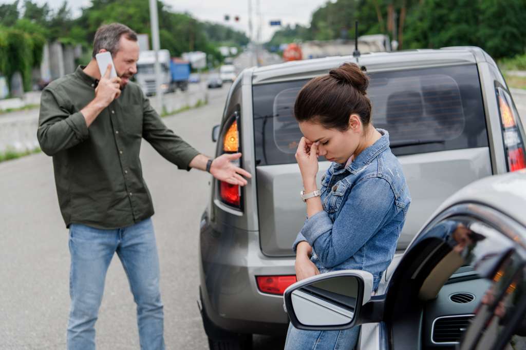 upset man and woman near cars after car accident