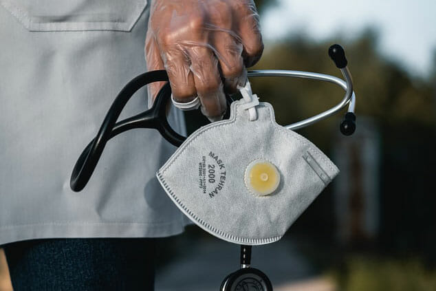 A doctor holding PPE and a stethoscope to depict how you should seek medical help during a pandemic