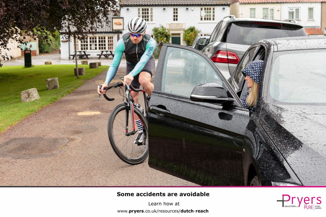 A poster showing a cyclist nearly getting knocked off, by the driver of a car, opening their door into the cyclist’s path, with some text at the bottom encouraging people to learn the Dutch Reach.