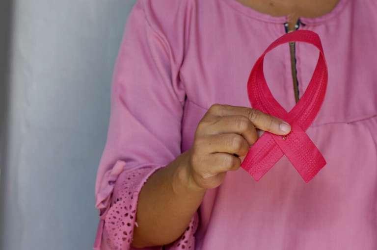 A photograph of a lady, dressed in pink and holding a pink ribbon, for breast cancer.